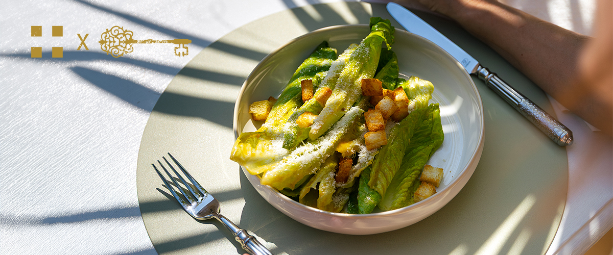 Insalata Caesar con crostini in un piatto fondo su una tavola apparecchiata con posate
