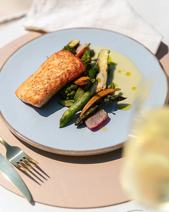 Gegrillter Lachs mit Gemüse, serviert auf einem Teller auf einem gedeckten Tisch 