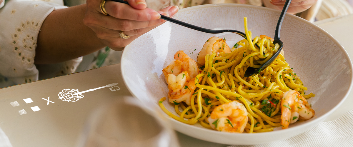 Spaghettis aux crevettes avec des couverts noirs dans un bol en porcelaine beige 