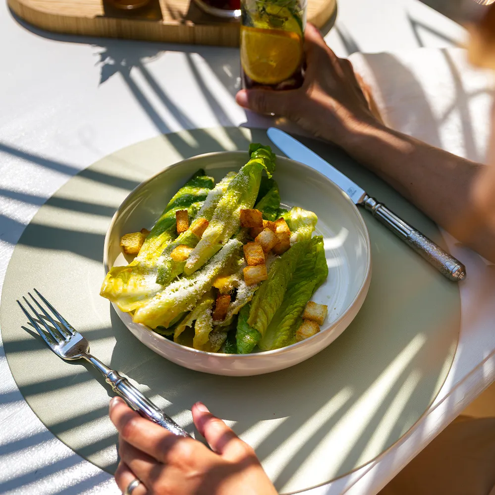 Caesar-Salat mit Salatblättern, Croutons und Parmesan, auf einem Teller angerichtet